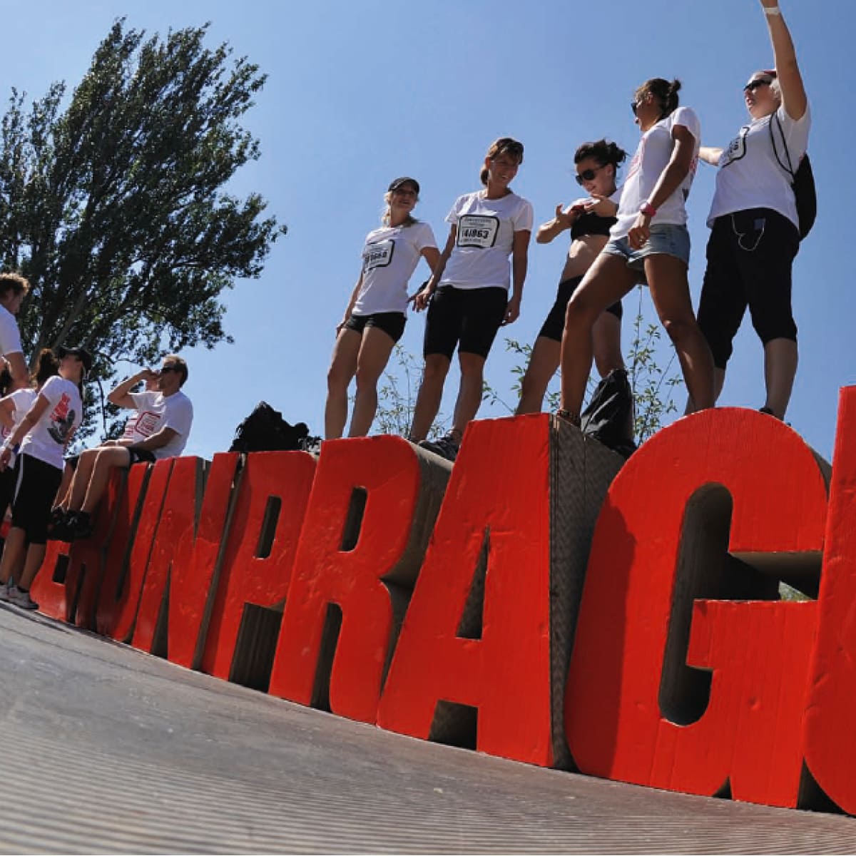 People standing on huge letters saying "We run Prague"