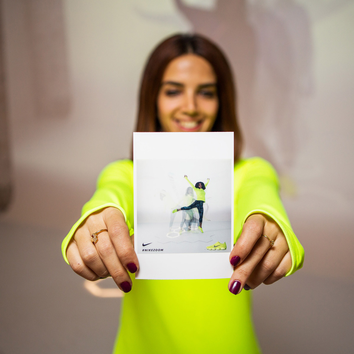 A woman holding an instax picture of another woman dancing in Nike event.